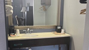 A bathroom with a large mirror, sink, and towel rack. - Western Motel (Jesup)
