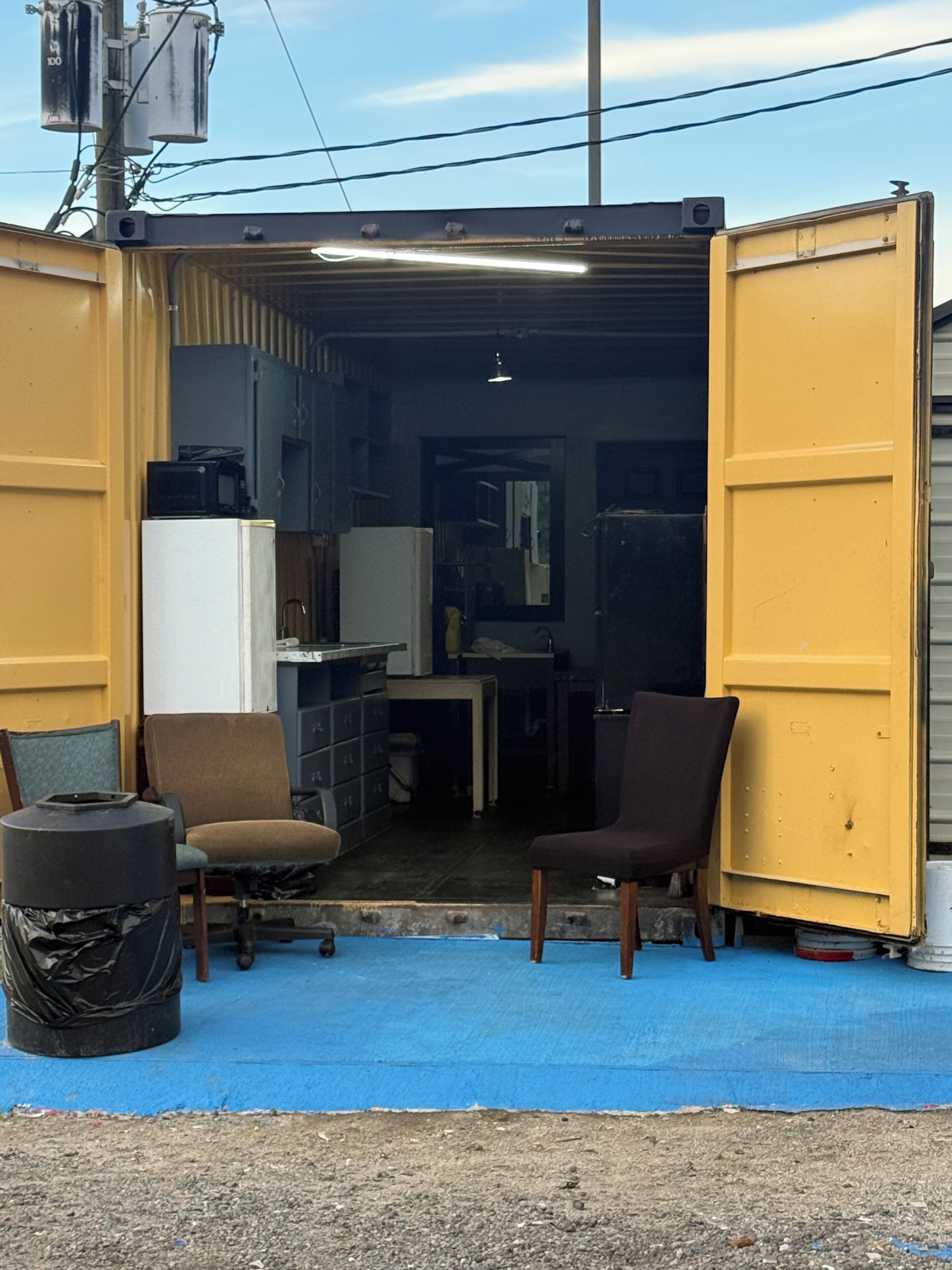 Un depósito con dos sillas, una mesita y un cubo de basura.
