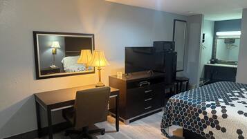 Habitació d'hotel amb escriptori, cadira, televisió, commode i llit.