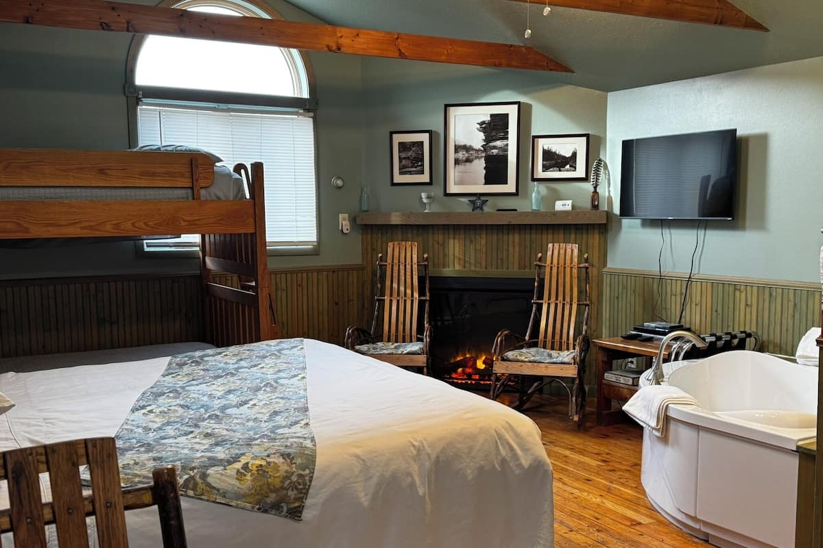 A cozy room with a bunk bed, a fireplace, a television, and a bathtub.