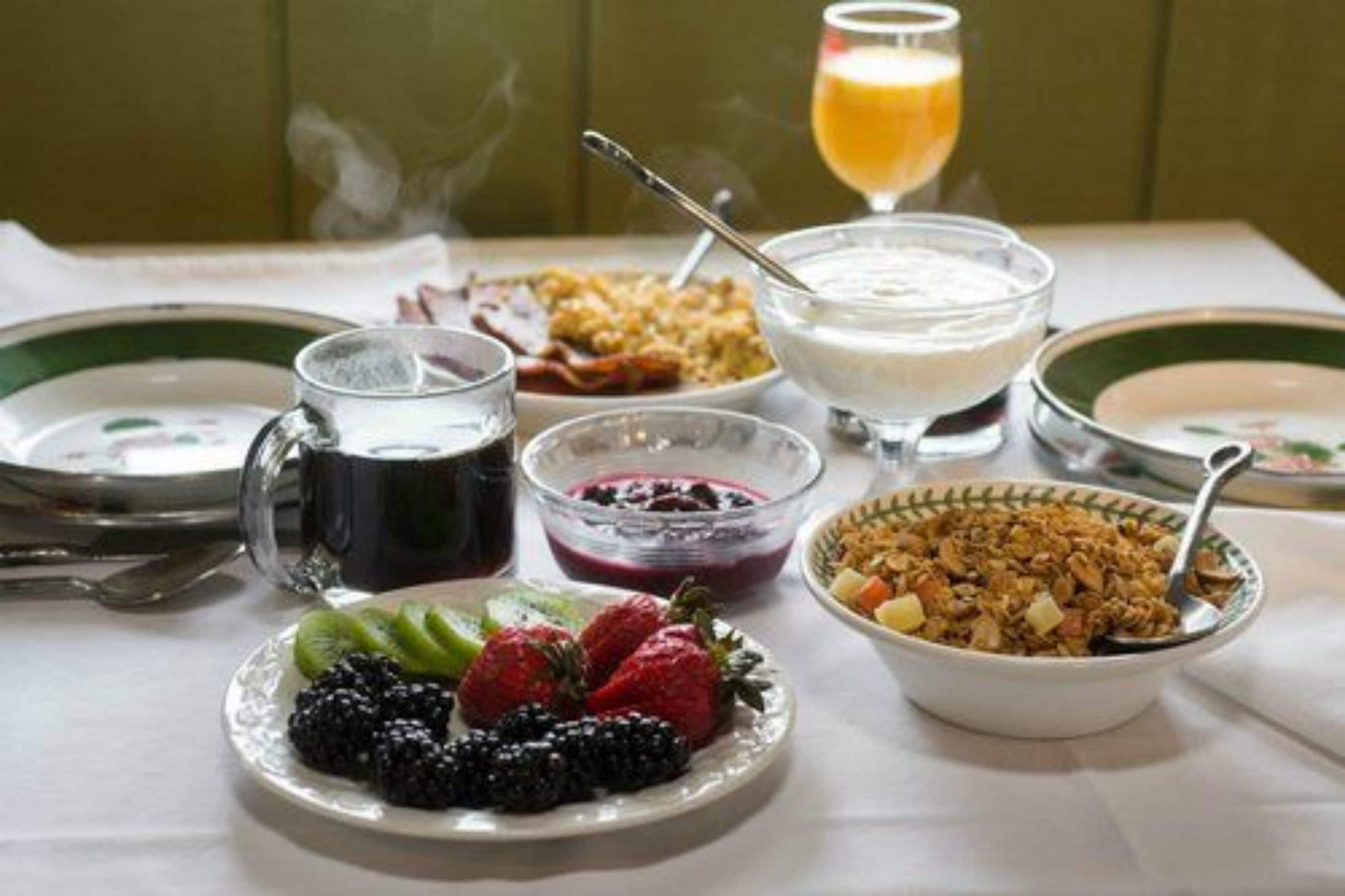 A breakfast setting with various dishes, including cereal, yogurt, and fruit.
