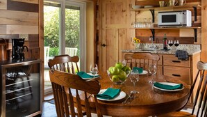 A wooden interior with a dining table set for two, a microwave, and a coffee maker. - Justin Trails Resort, LLC. (Sparta)