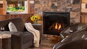 A cozy living room with a stone fireplace, leather sofas, and a view of a garden through a window. - Justin Trails Resort, LLC. (Sparta)