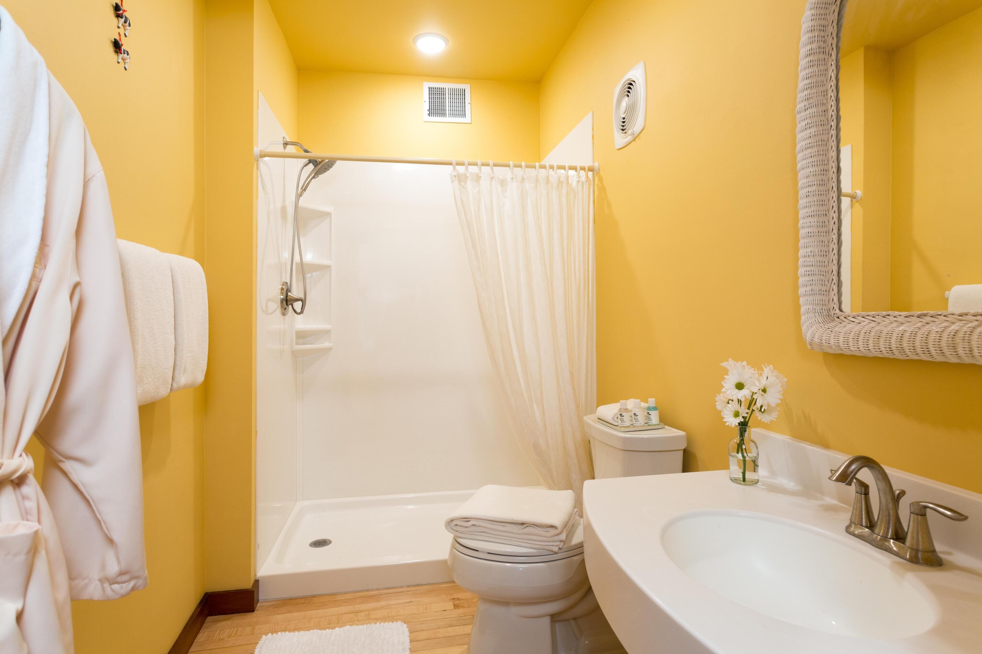 A bathroom with a shower, toilet, sink, and a towel rack.