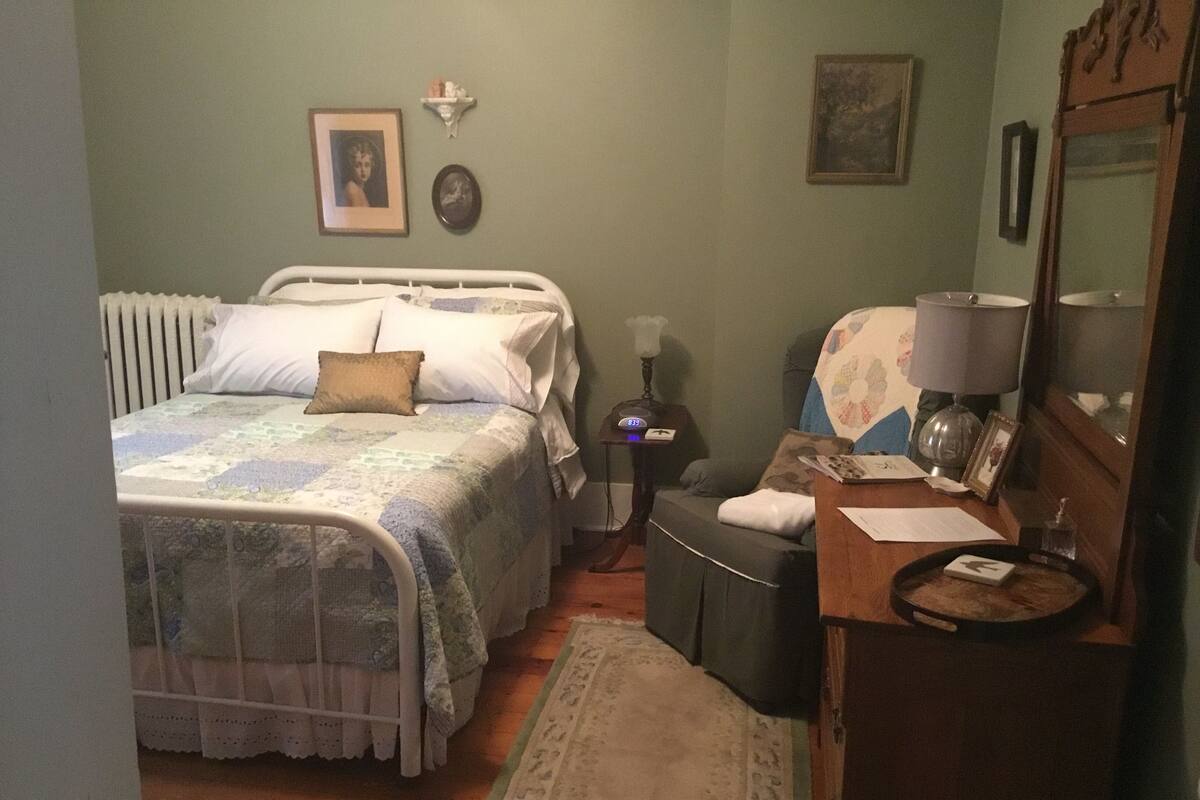 Una camera da letto con un letto, un comodino, una sedia e una cassettiera.