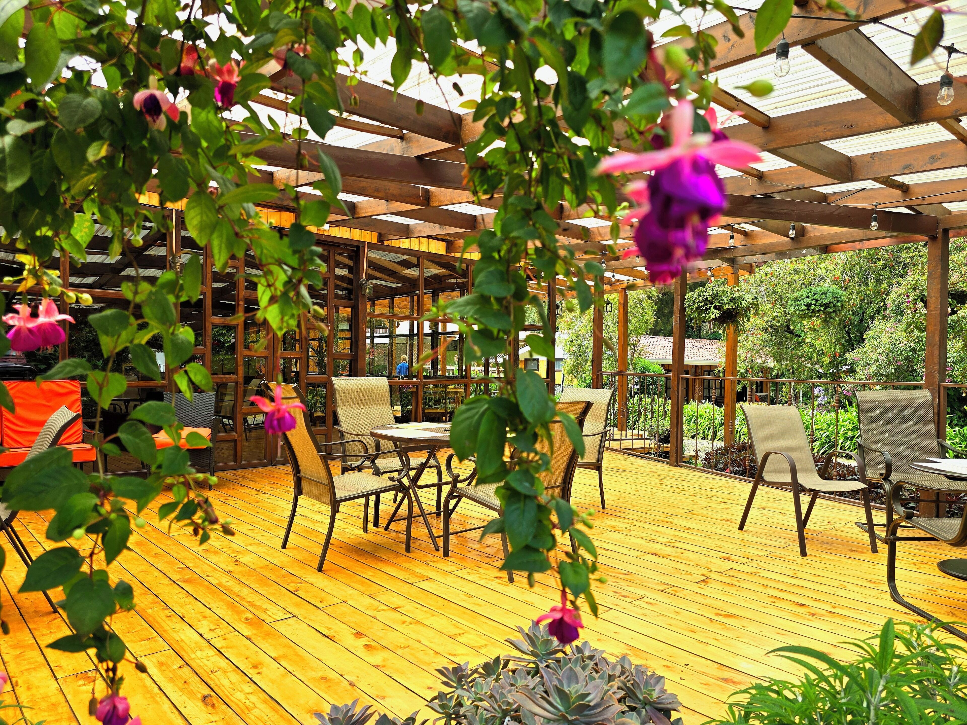 An outdoor patio with wooden flooring, metal-framed chairs, and tables.