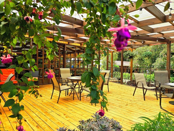 An outdoor patio with wooden flooring, metal-framed chairs, and tables.