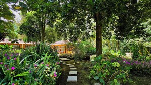 Een tuin met een pad van stenen dat leidt naar een gebouw met een pannendak.