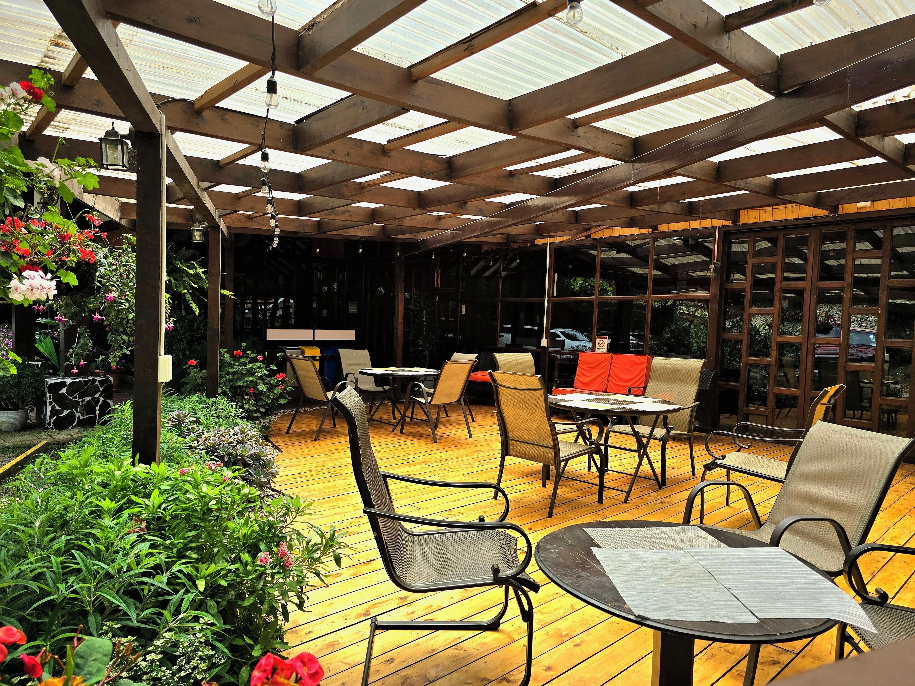 Eine Terrassengruppe mit Holzboden, Metallstühlen und Tischen.