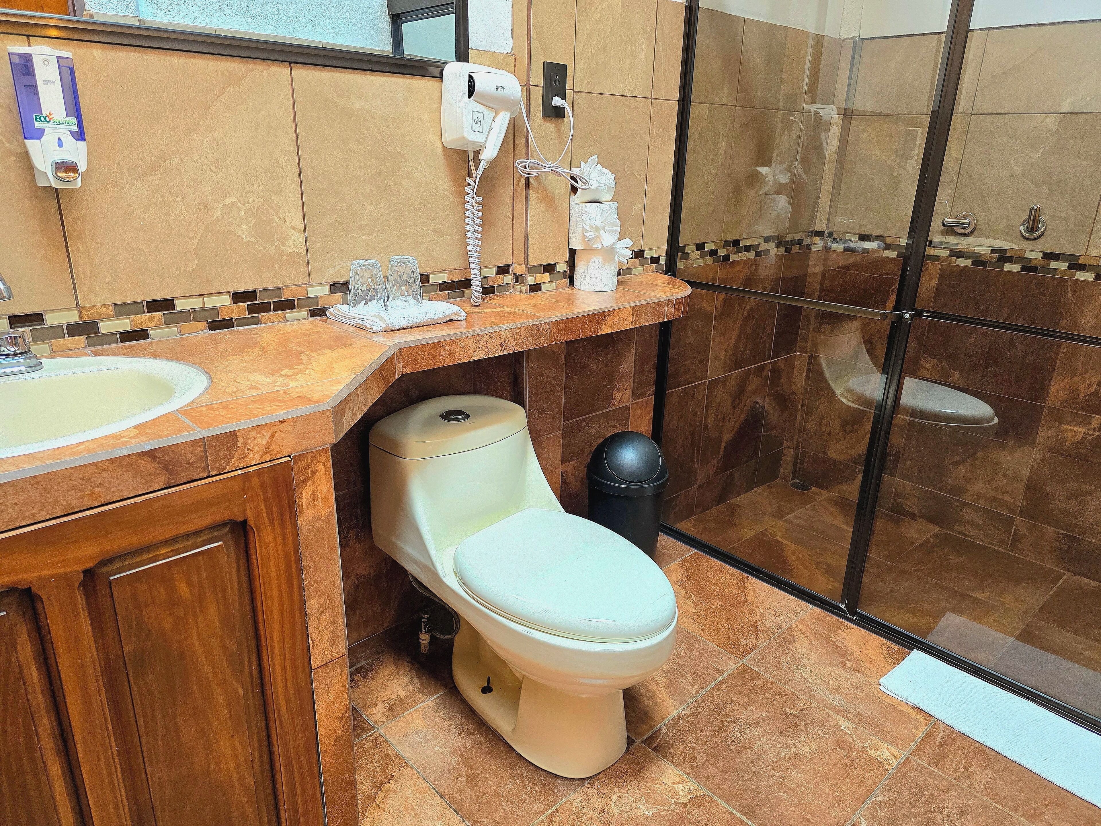 Een badkamer met toilet, wastafel en een douchecabine van glas.