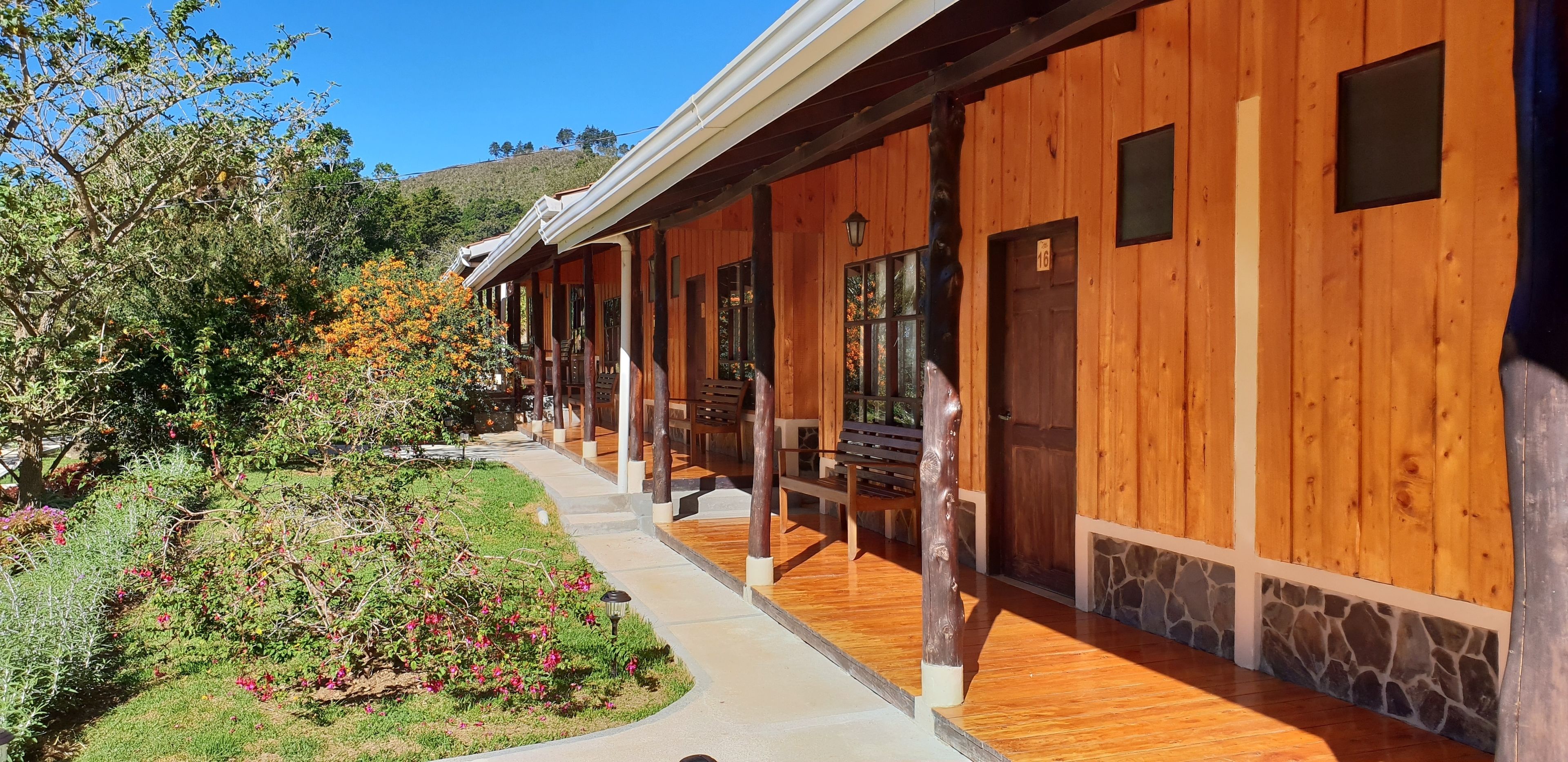 A wooden building with a covered walkway, stone accents, and a bench.