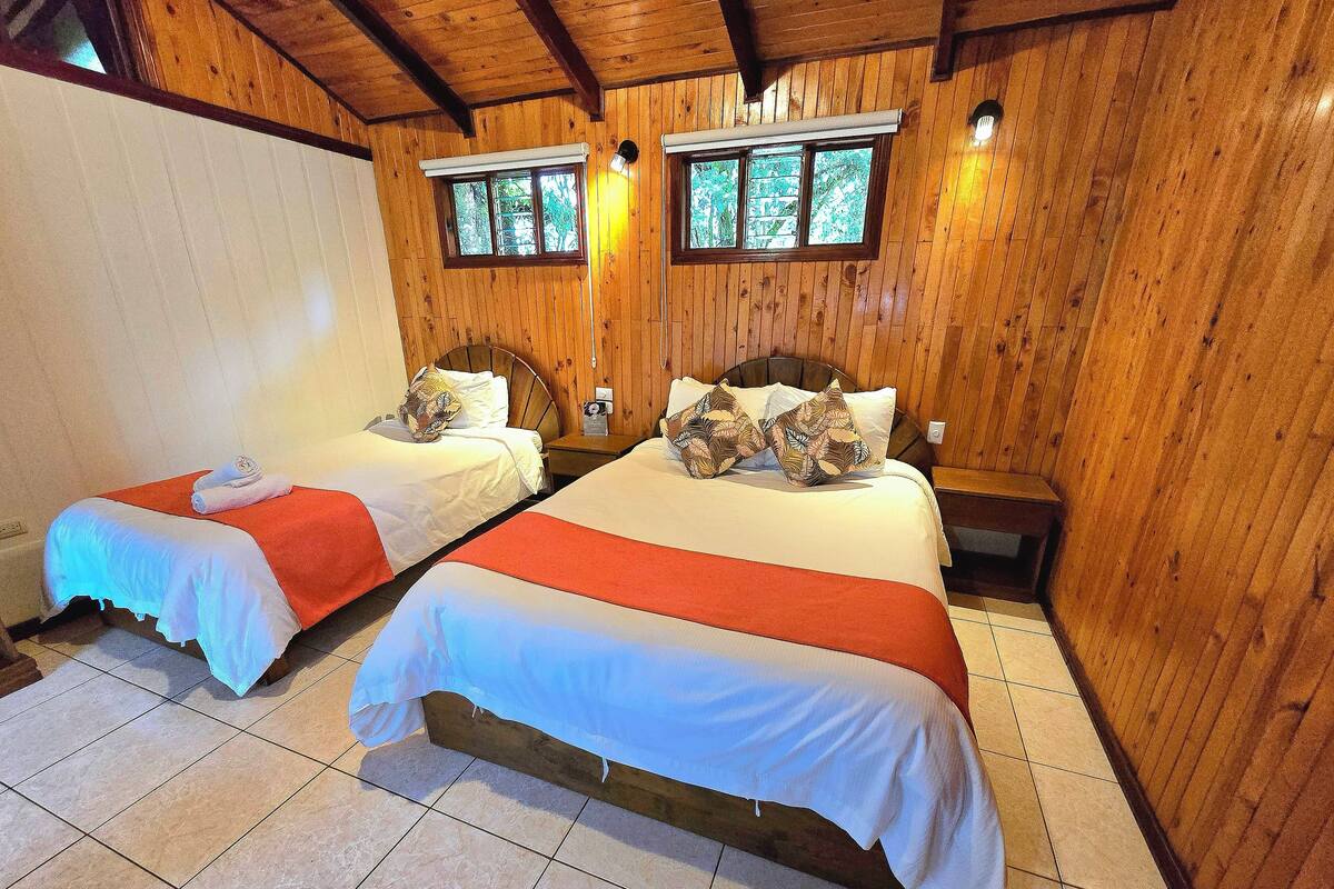 Habitación con dos camas, paredes de madera y suelo de baldosas.