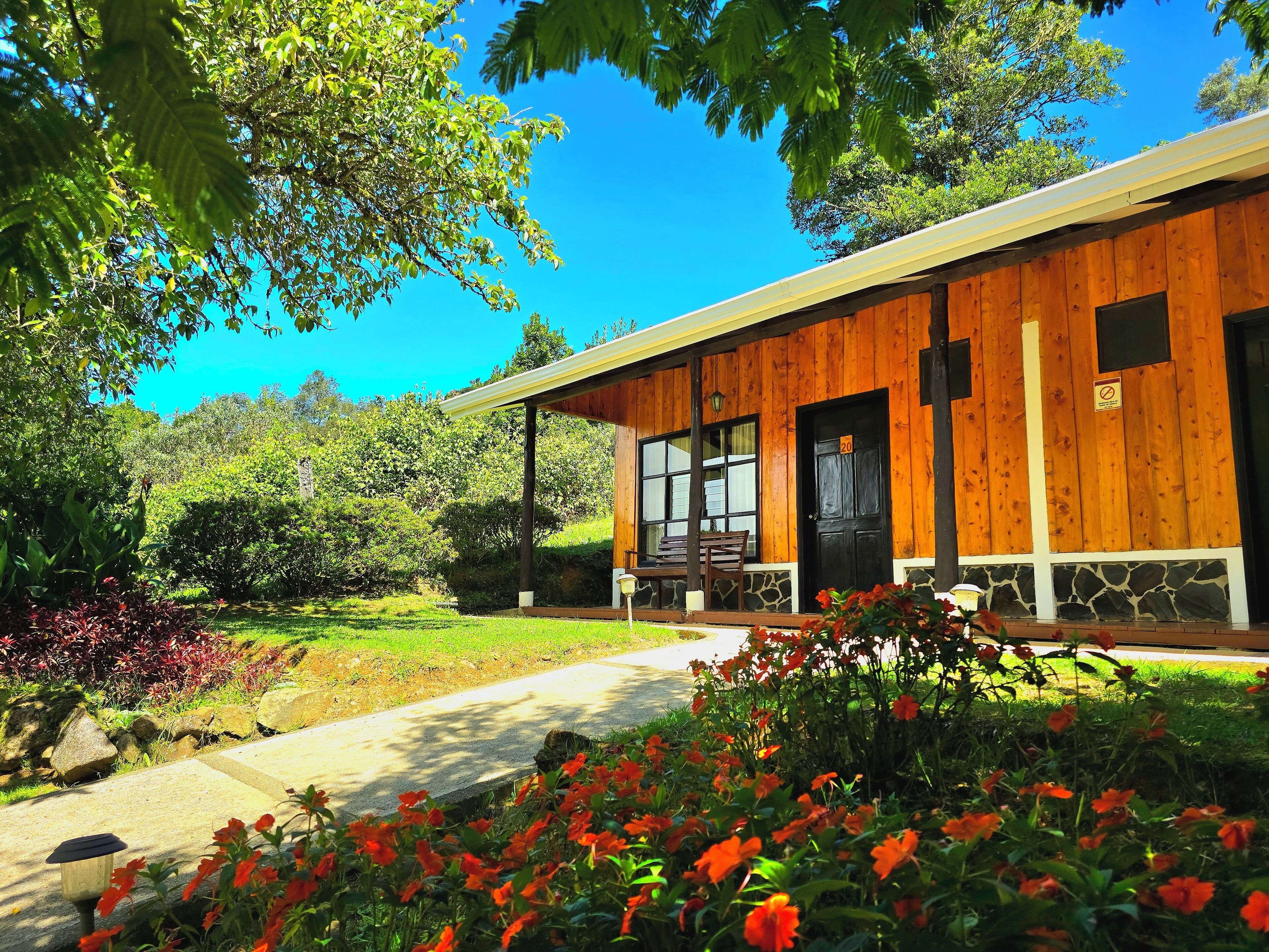 A wooden building with a stone foundation, a porch with a bench, and a pathway leading to the entrance.
