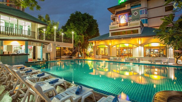 Une piscine avec des chaises longues, un espace bar et un bâtiment doté d’un balcon.