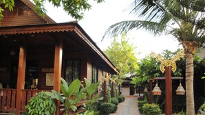 Un bâtiment traditionnel en bois, doté d’un porche couvert, de plantes en pot et d’un chemin en briques.