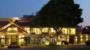 Un hôtel au style architectural traditionnel, doté d’une entrée imposante, d’un toit décoratif et d’une enseigne lumineuse.