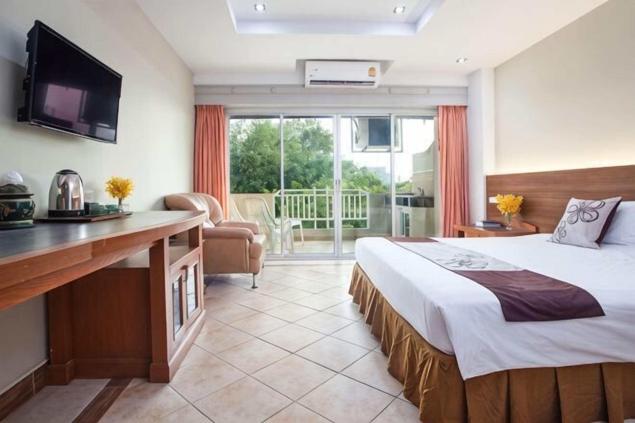 Habitación de hotel con cama, escritorio, televisión y balcón con vistas, además de una puerta corrediza.