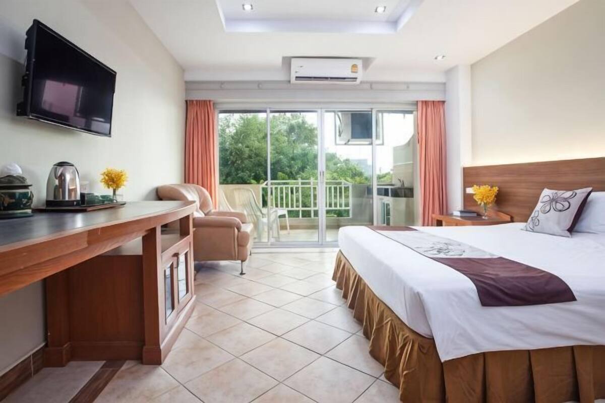 Habitación de hotel con cama, escritorio, televisión y balcón con vistas, además de una puerta corrediza.