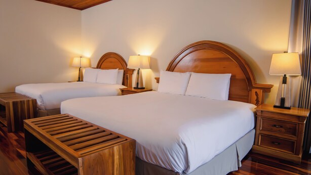 A hotel room with two single beds, a wooden bench, and a nightstand with a lamp. - Fondavela Hotel (Monteverde)