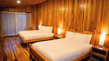 Habitación de hotel con dos camas, paredes y piso de madera.