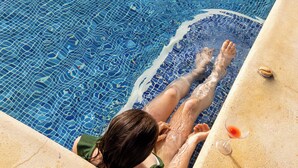 Una persona relajándose en una piscina con una copa de vino al borde.
