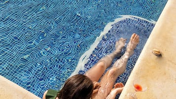 Una piscina al aire libre, sillones reclinables de piscina