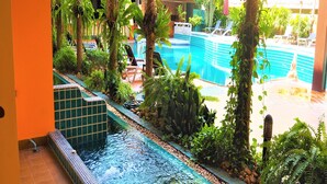A pool area with a water feature, surrounded by lush greenery and lounge chairs. - Mind Resort Pattaya (Pattaya)