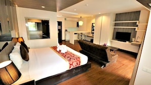 A modern hotel room with a large bed, a sofa, a TV, and a kitchenette in the background. - Mind Resort Pattaya (Pattaya)