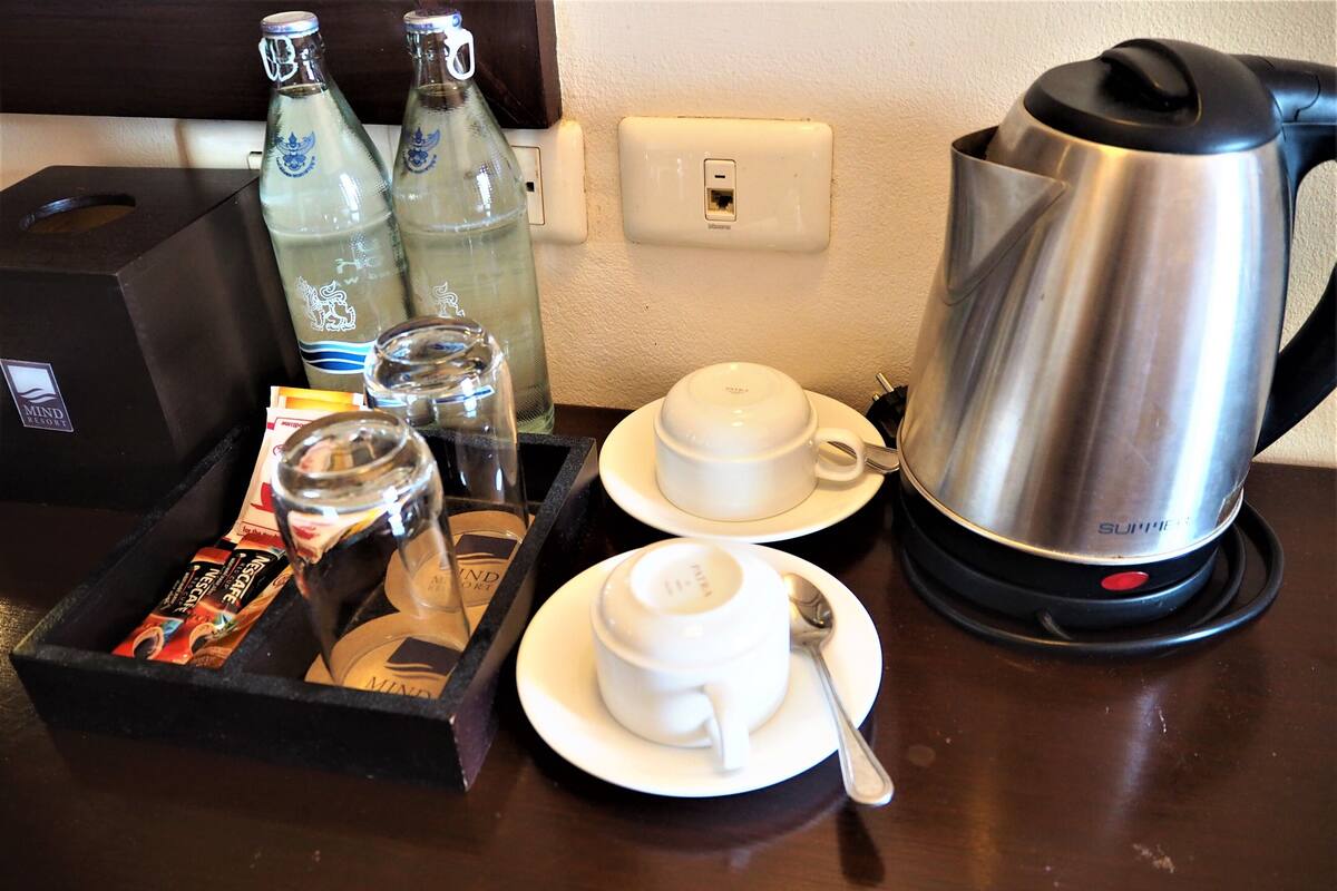 Ein Tablett mit einer Kaffeemaschine, zwei Tassen, einem Löffel und einer Packung Teebeuteln.
