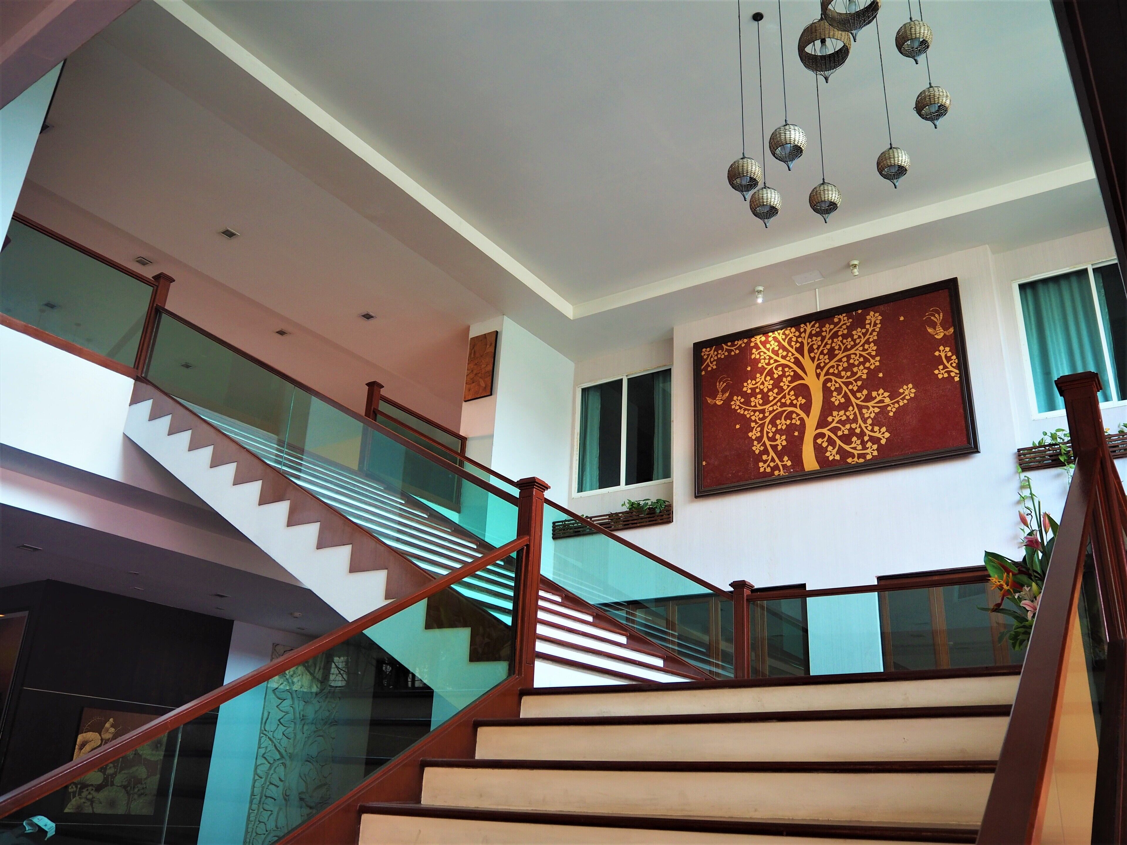 Ein modernes Interieur mit einer Treppe, Glasgeländern und einem großen Wandbild.