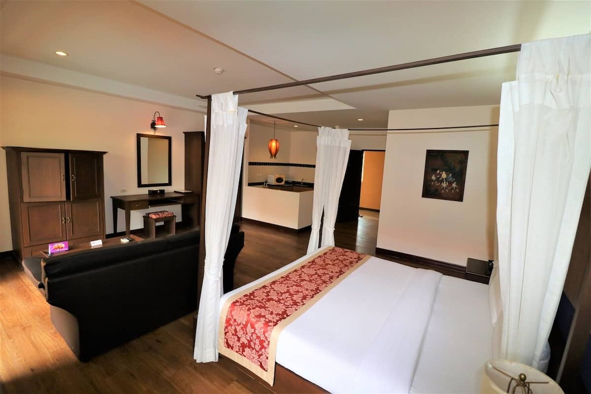 Ein Hotelzimmer mit Himmelbett, Schreibtisch und Stuhl, Schminktisch mit Spiegel und einer kleinen Sitzecke.