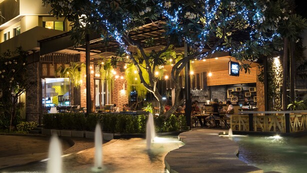 An outdoor dining area with a fountain, wooden pergola, and string lights. - Mind Resort Pattaya (Pattaya)