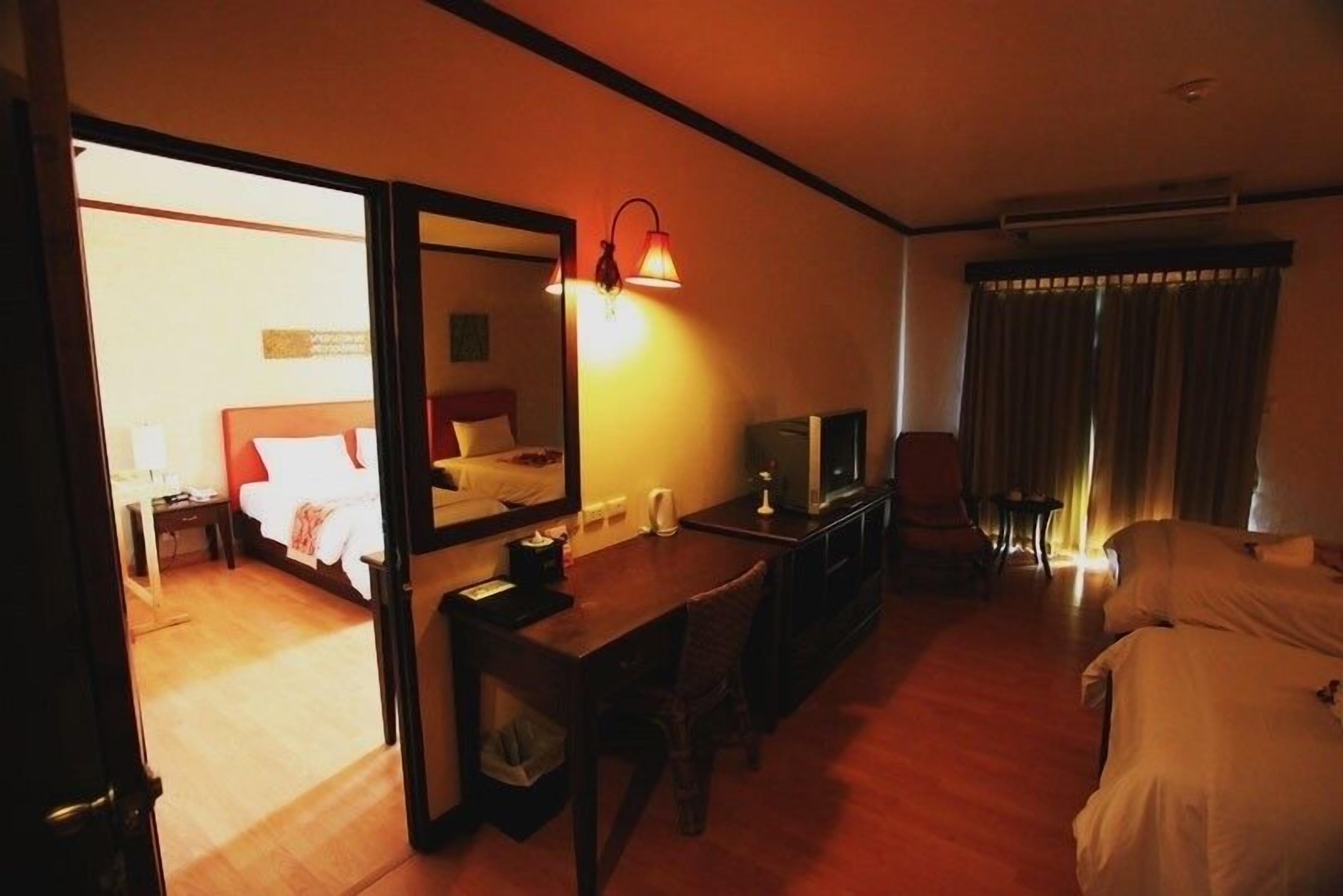 A hotel room with a bed, a desk, a chair, a television, and a mirror.