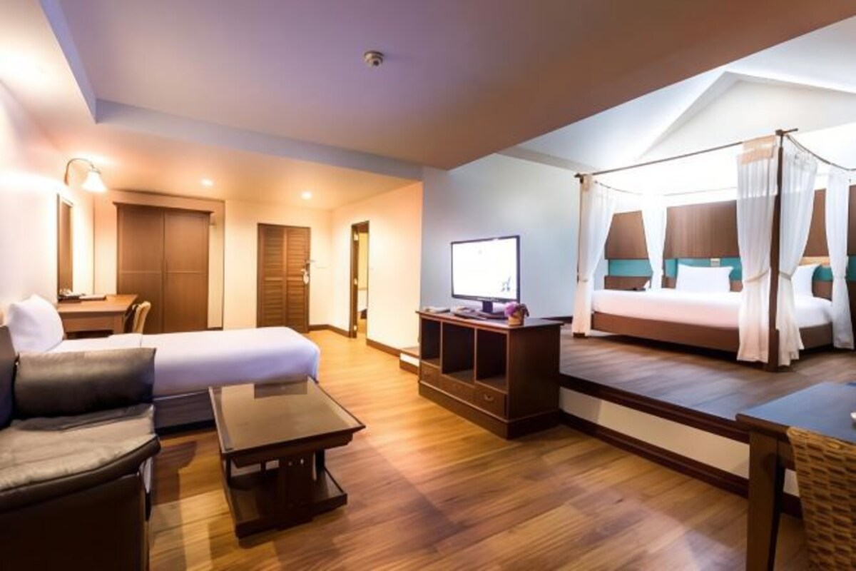 A hotel room with a bed, a sofa, a TV, and a desk.