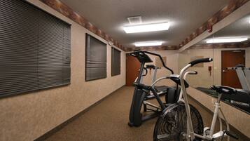 A hallway with exercise equipment, including a stationary bike and an elliptical machine.