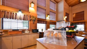 A kitchen with a counter, cabinets, a microwave, and a fruit display. - Kelly Inn & Suites Mitchell South Dakota (Mitchell)