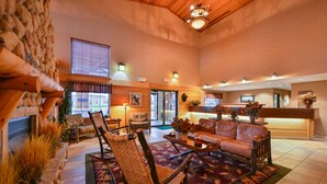 A spacious lobby with a stone wall, a reception desk, a fireplace, and a seating area with a patterned rug. - Kelly Inn & Suites Mitchell South Dakota (Mitchell)