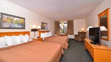 A hotel room with two beds, a desk, a chair, a television, and a window with curtains.