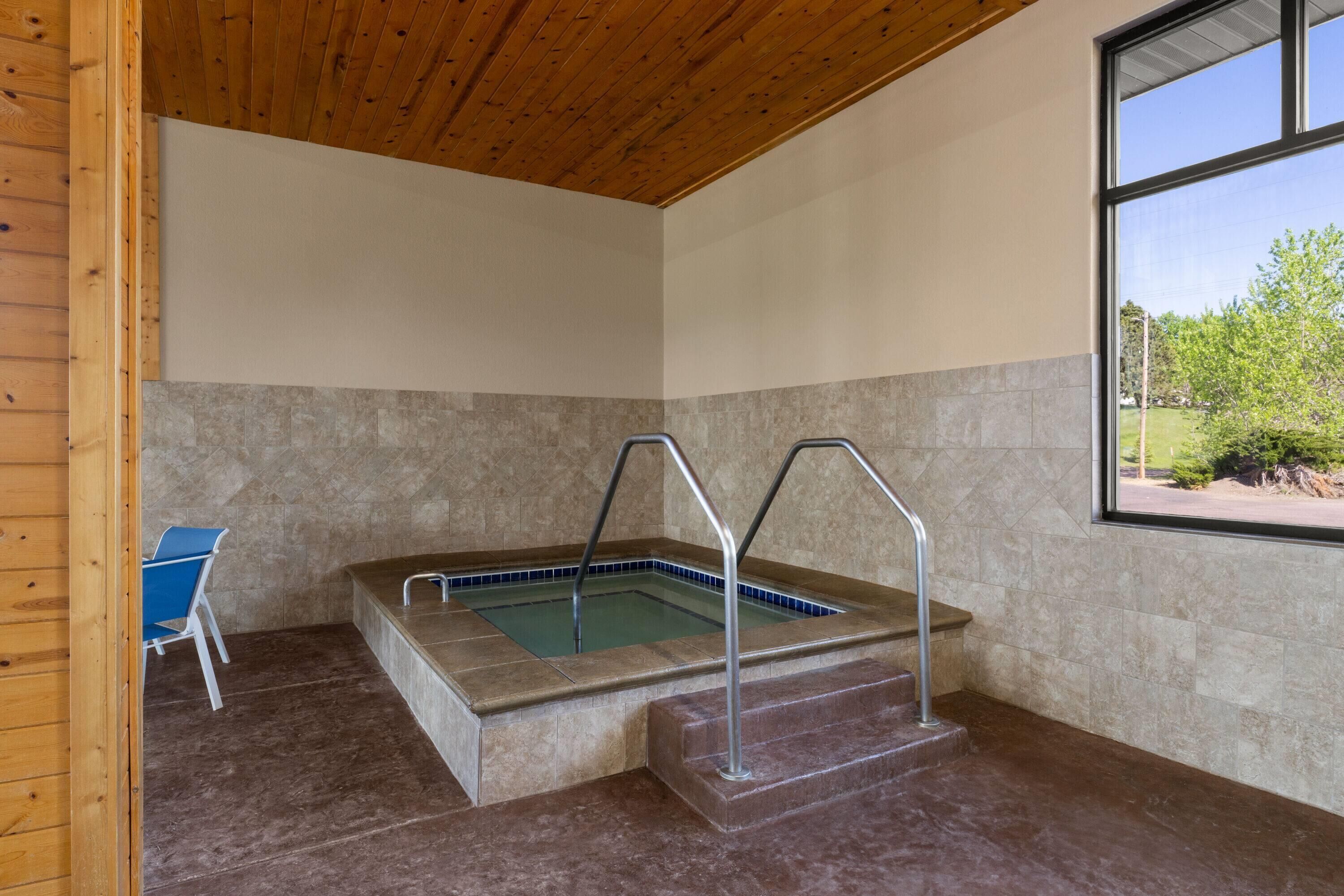 A spa area with a hot tub, a chair, and a view of the outdoors.