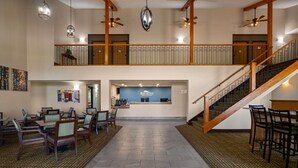 A hotel lobby with a reception desk, seating area, and a staircase.