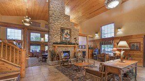 A spacious lodge interior with a stone fireplace, wooden furniture, and large windows. - Best Western Plus Kelly Inn & Suites (Fargo)