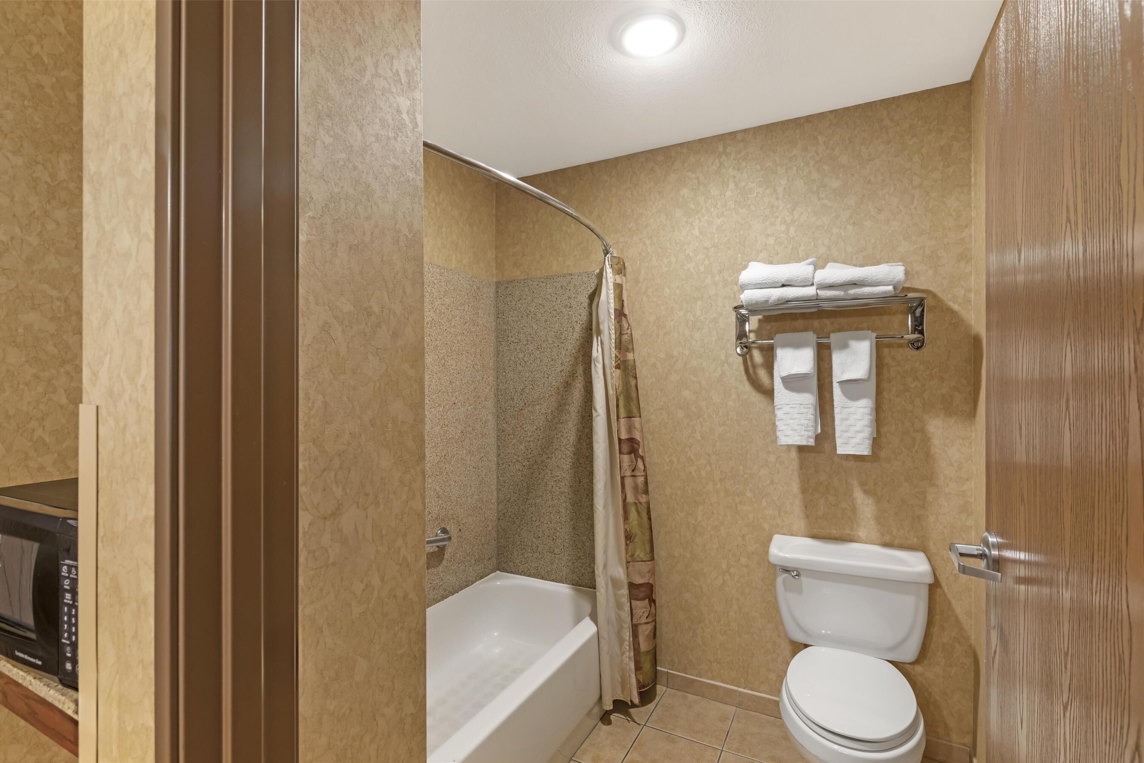 A bathroom with a bathtub, toilet, and shower curtain.