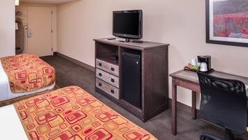 A hotel room with two beds, a desk with a computer, a TV, and a coffee maker.