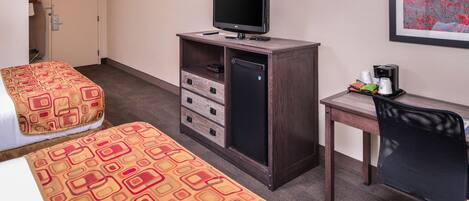 A hotel room with two beds, a desk with a computer, a TV, and a coffee maker.