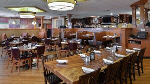 A restaurant with multiple dining areas, including booths and tables, with a bar area visible in the background.