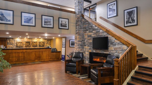A lobby with a stone fireplace, leather seating, a bar area, and a staircase.