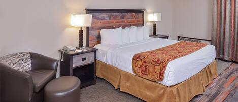 A hotel room with a bed, a chair, a nightstand, and a lamp.