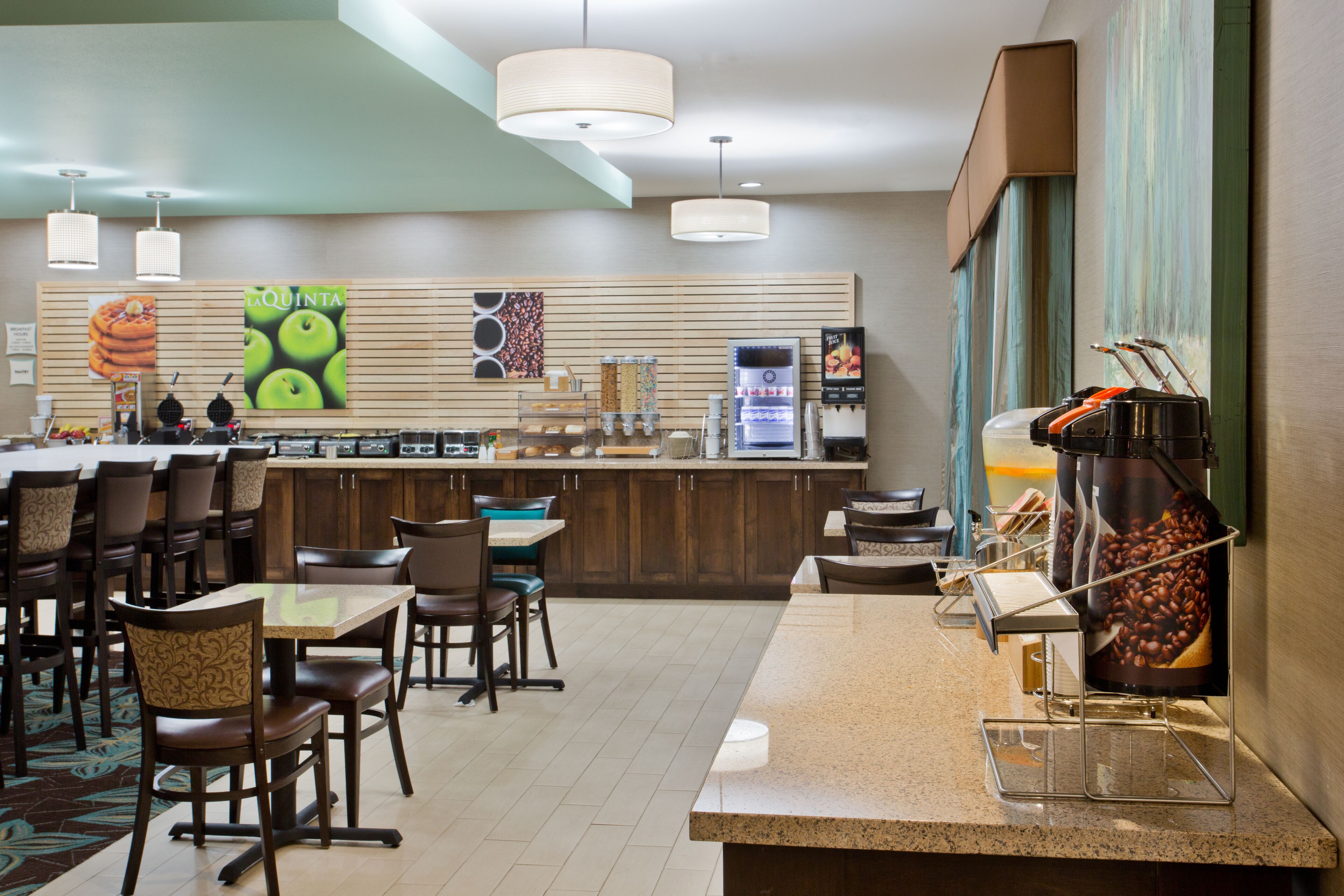 Um restaurante com balcão, cadeiras, mesas e uma máquina de café.