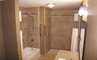 Un baño moderno con ducha a ras de suelo, bañera y tocador con espejo.