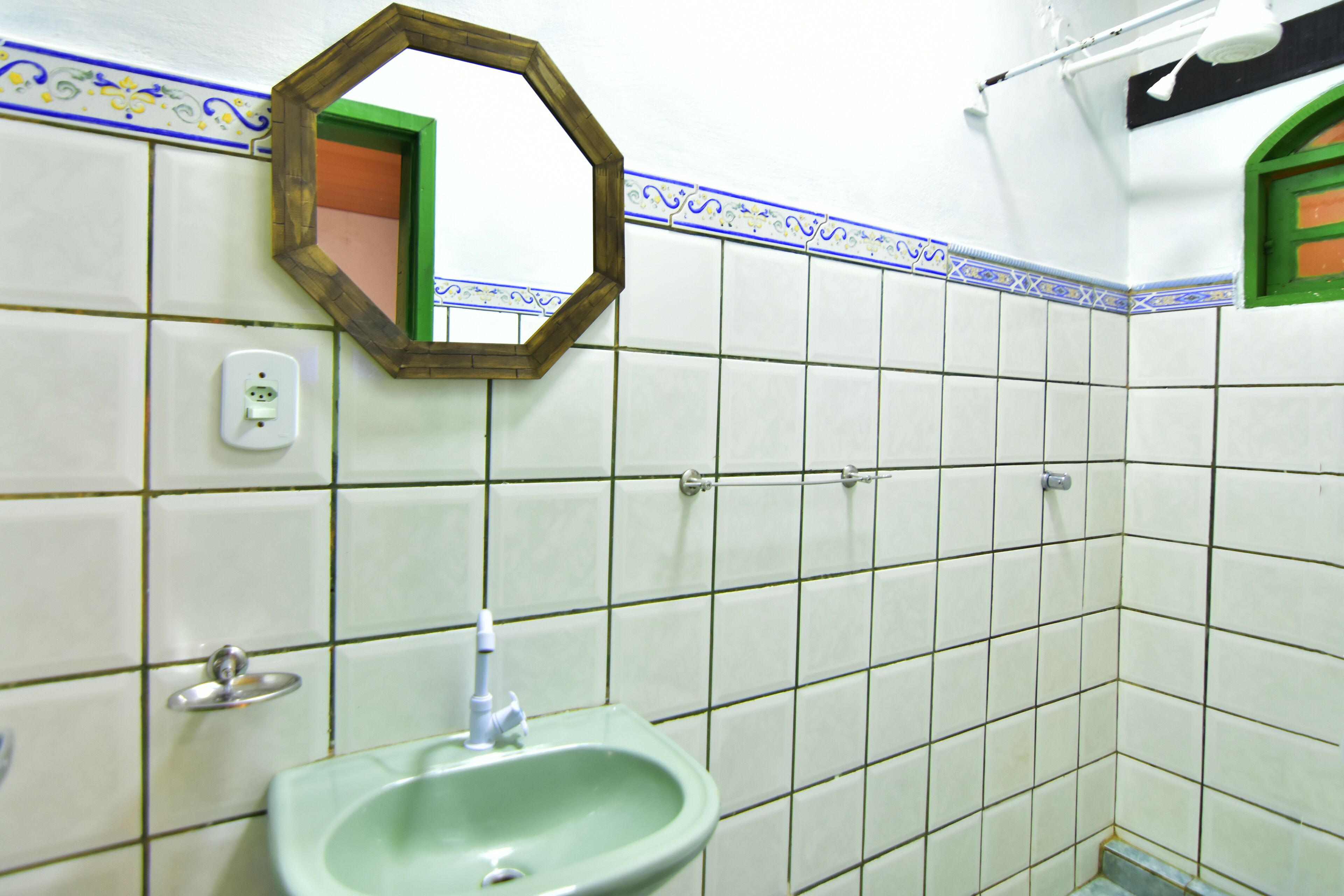 A bathroom with a green sink, a mirror, and tiled walls.